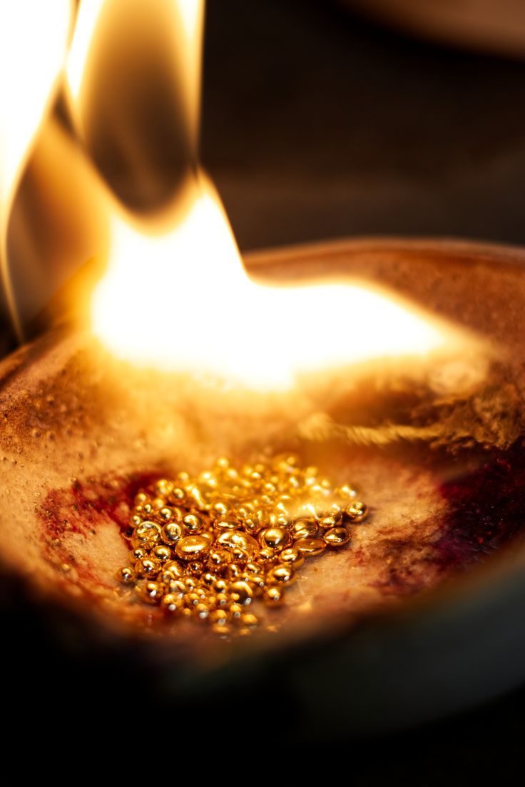 Molten gold droplets forming under flame